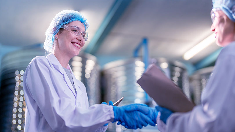 Mitarbeiterinnen in Schutzkleidung besprechen Ergebnisse in einer Produktionsumgebung