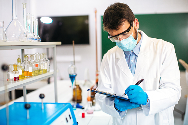 Mann der mit einem Klammbrett in einem Chemielabor etwas kontrolliert