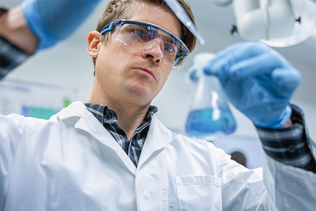 Wissenschaftler im Labor analysiert Fl&uuml;ssigkeit im Erlenmeyerkolben