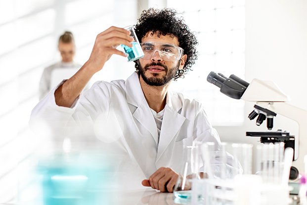Laborant beim kontrollieren einer Fl&uuml;ssigkeit im Reagenzglas